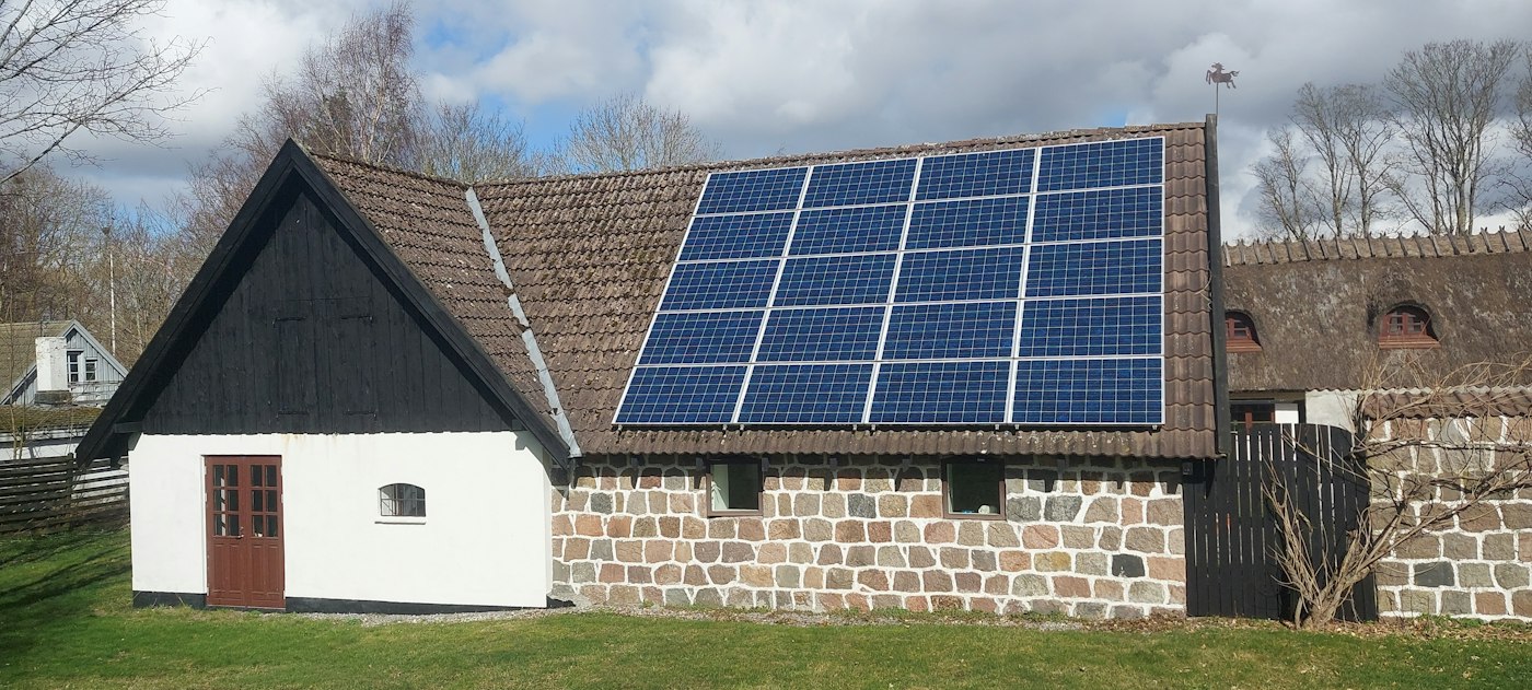 Weißes Landhaus mit Solarmodulen auf dem Ziegeldach