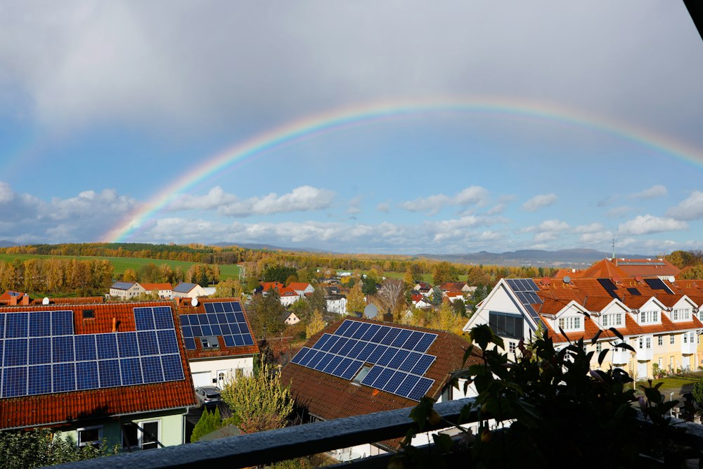Reihenhaussiedlung mit Solarmodulen, darüber ein Regenbogen